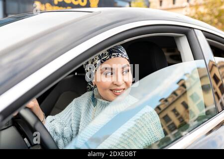 Smiling woman looking away while sitting in car Stock Photo