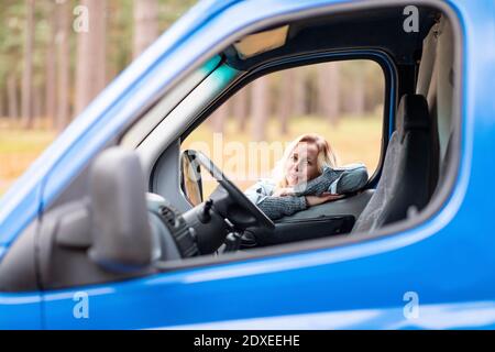 Smiling woman looking through window from her camper van Stock Photo