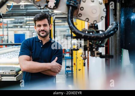 Smiling male worker with arms crossed standing at industry Stock Photo