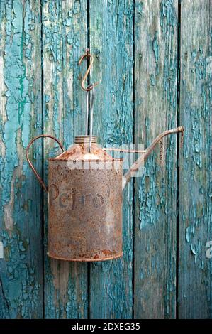 Rusty oil can hanging on old wooden wall Stock Photo