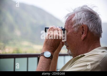 Senior man looking at view through binoculars Stock Photo