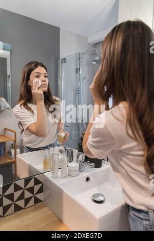Young woman doing make-up while standing in bathroom at home Stock Photo