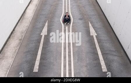 Young man sitting on road marking Stock Photo