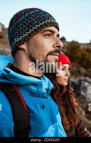 Thoughtful couple looking away while hiking on mountain during vacation Stock Photo