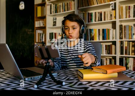 Boy vlogging with smart phone at table in living room Stock Photo