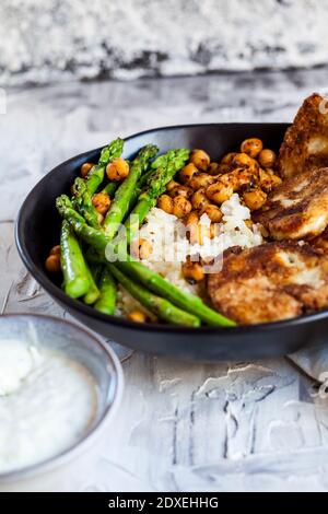 Dipping sauce and bowl of rice with chick-peas, asparagus stalks and fried halloumi cheese Stock Photo