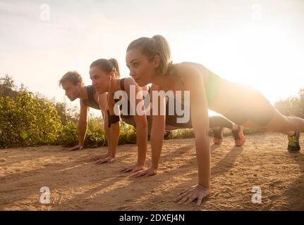 Sports people exercising together while doing push-ups on mountain path Stock Photo