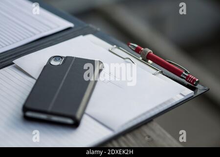 Clipboard with smart phone and pen on desk Stock Photo