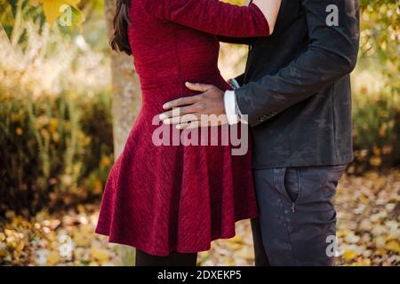 Young man hands on pregnant woman's stomach while standing in park during autumn Stock Photo