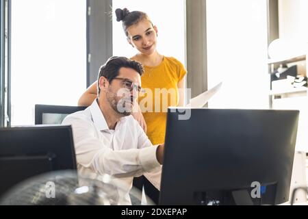Businessman and woman using computer while working in office Stock Photo