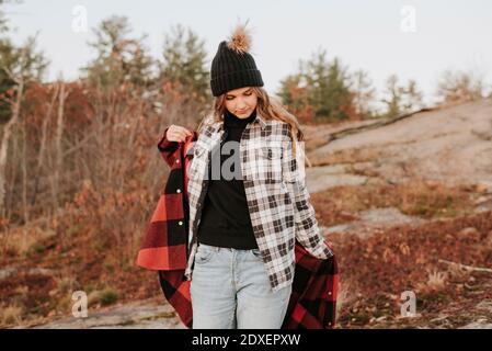 Young woman putting on second shirt during autumn hike Stock Photo