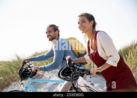 Couple with bicycles walking against clear sky Stock Photo