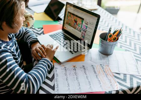 Boy watching online video on laptop while sitting at table Stock Photo