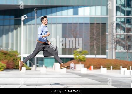 Happy businessman cheering while running on footpath Stock Photo