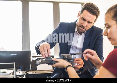 Businessman examining quadcopter with colleague at office Stock Photo