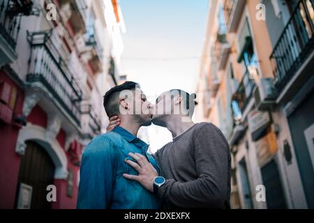 Affectionate gay couple kissing in city Stock Photo