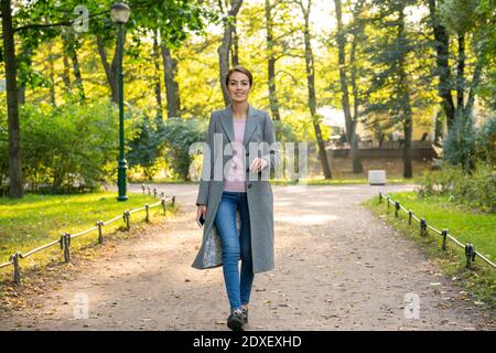 Happy businesswoman during autumn walking in park Stock Photo