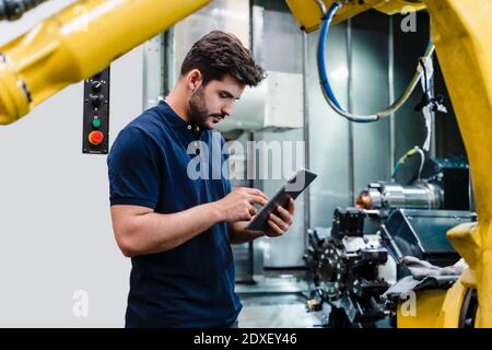 Male worker using digital tablet while standing in factory Stock Photo