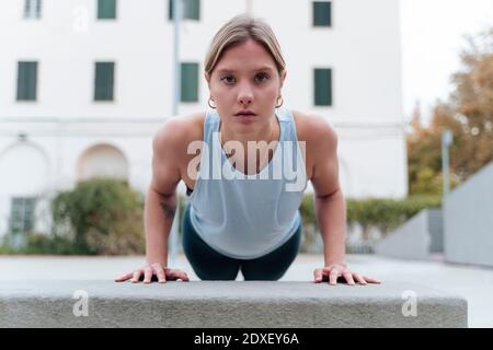 Young woman doing push-ups outdoors Stock Photo