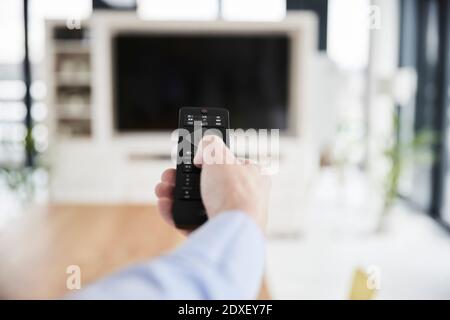Man using remote control at home Stock Photo
