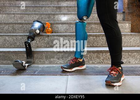 Young sportswoman with prosthetic leg standing by artificial limb on steps Stock Photo