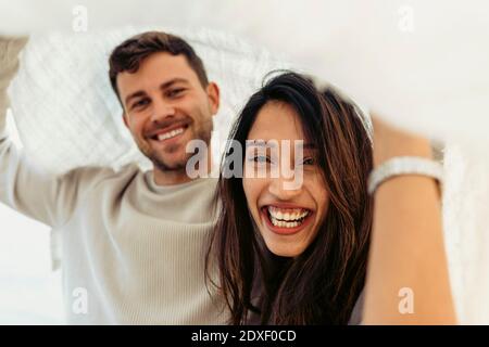 Happy young couple below shawl spending leisure time outdoors Stock Photo