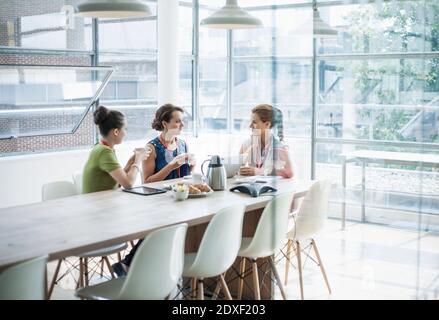 Female professionals discussing in board room while having coffee at office Stock Photo