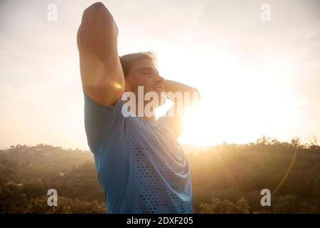 Man stretching arms while standing against sky Stock Photo
