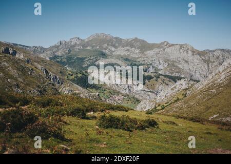 Distant view of Bejes village against mountain range on sunny day, Picos de Europa National Park, Asturias, Spain Stock Photo
