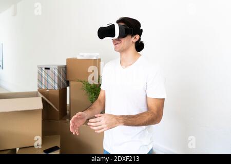 Smiling young man wearing virtual reality simulator at new apartment Stock Photo