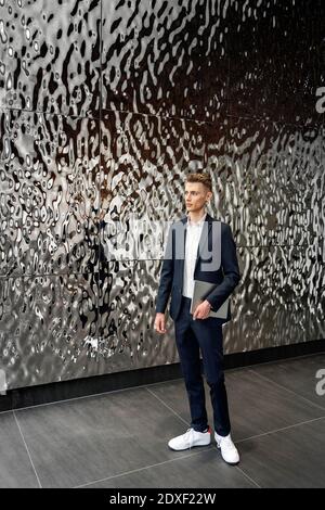 Young entrepreneur holding digital tablet while standing by wall Stock Photo