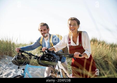 Young man and woman walking with bicycles against clear sky Stock Photo