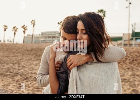 Young man embracing woman at beach during weekend Stock Photo