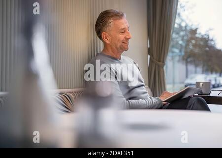 Smiling businessman using digital tablet while sitting at modern cafe Stock Photo