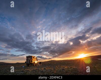 Cloudy sky over off-road car parked in remote Icelandic location at sunset Stock Photo