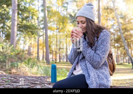 Female hiker smelling tea while sitting in Cannock Chase forest Stock Photo