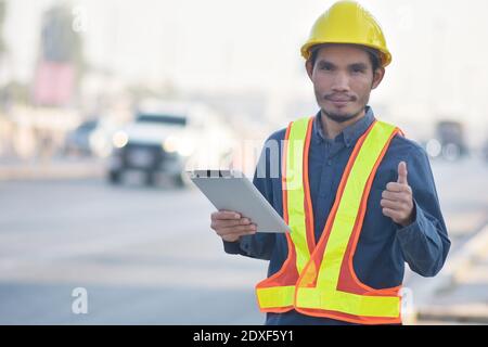 Engineering Holding tablet Highway transportation on road background,Engineer use tablet technology analysis data to planing work construction Stock Photo