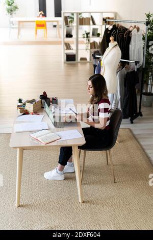 Young female designer using laptop while sitting in studio Stock Photo