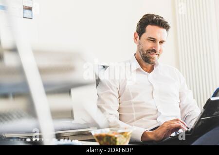 Businessman using digital tablet during lunch break at office Stock Photo