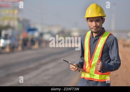 Engineering hold tablet is checking  surface of road in the road construction area. Land transportation system Stock Photo