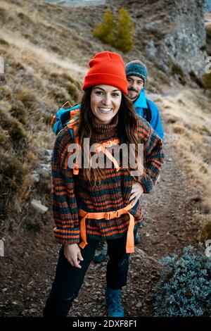 Smiling woman hiking with boyfriend on rocky mountain during vacation Stock Photo