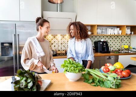 Smiling females colleagues cooking food together in office kitchen Stock Photo