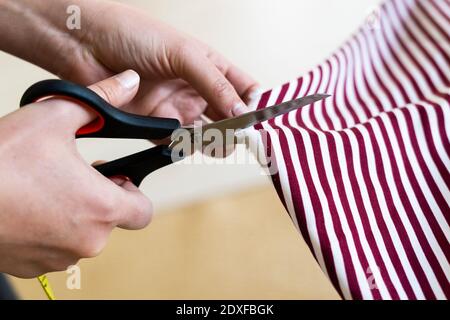Female designer's hand cutting fabric in studio
