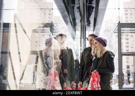 Young woman doing window shopping while standing with man by store window Stock Photo