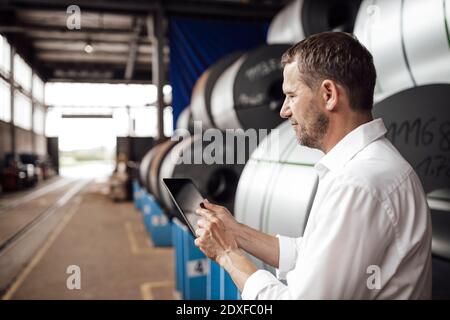 Male owner using digital tablet while standing in factory Stock Photo