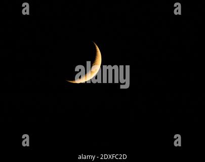 Waxing Crescent moon glowing against pitch black sky at night Stock Photo