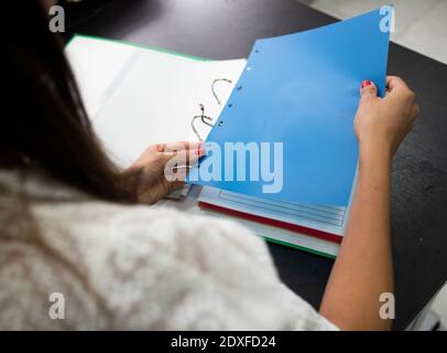 Businesswoman attaching paper in file while sitting on desk at office Stock Photo