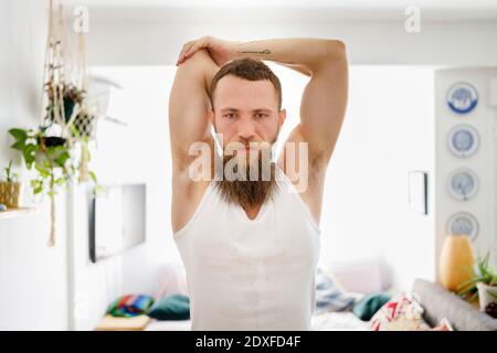 Bearded man doing stretching exercise while standing at home Stock Photo