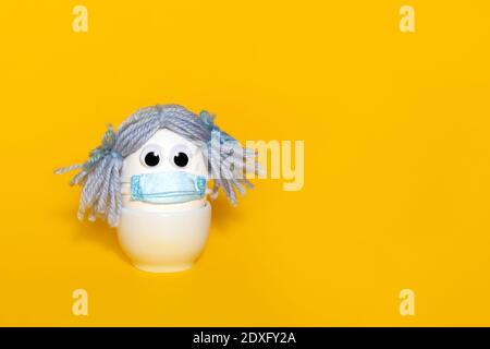 Easter in new reality. Corona virus protection concept. Creative easter idea. Egg in real medical mask. Copy space. Egg woman in mask. Stock Photo