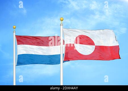 Netherlands and Greenland two flags on flagpoles and blue sky